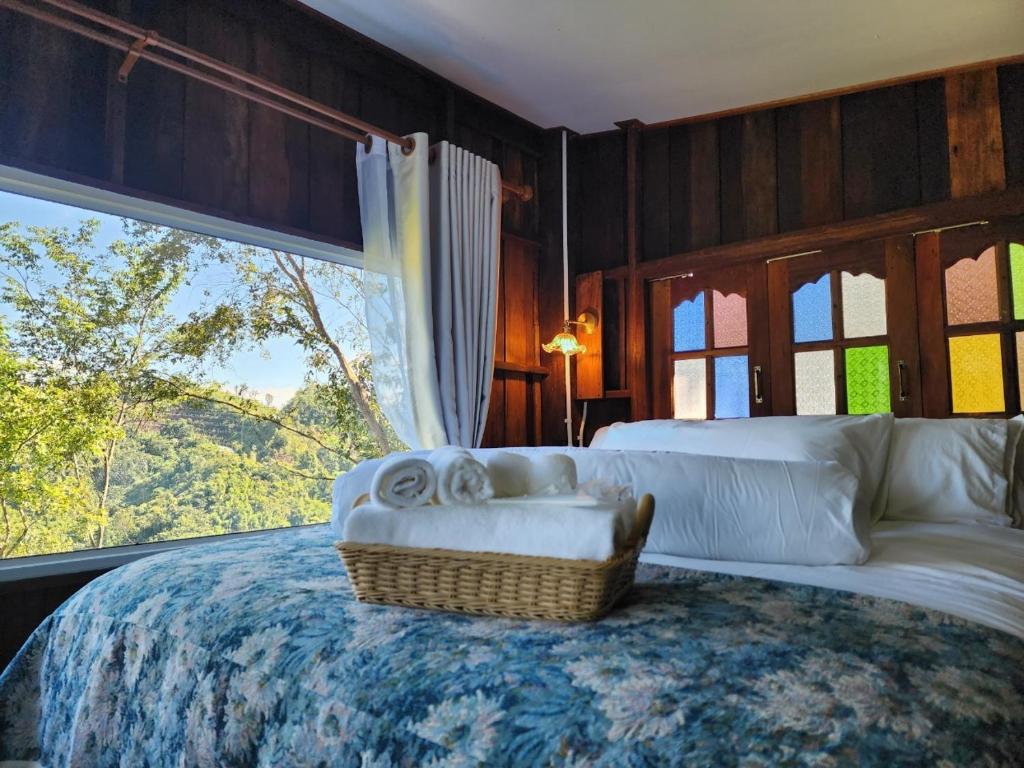 a bedroom with a bed with a large window at บ้านเล็กในป่าใหญ่ at น่าน Little House In the Forest at Nan 