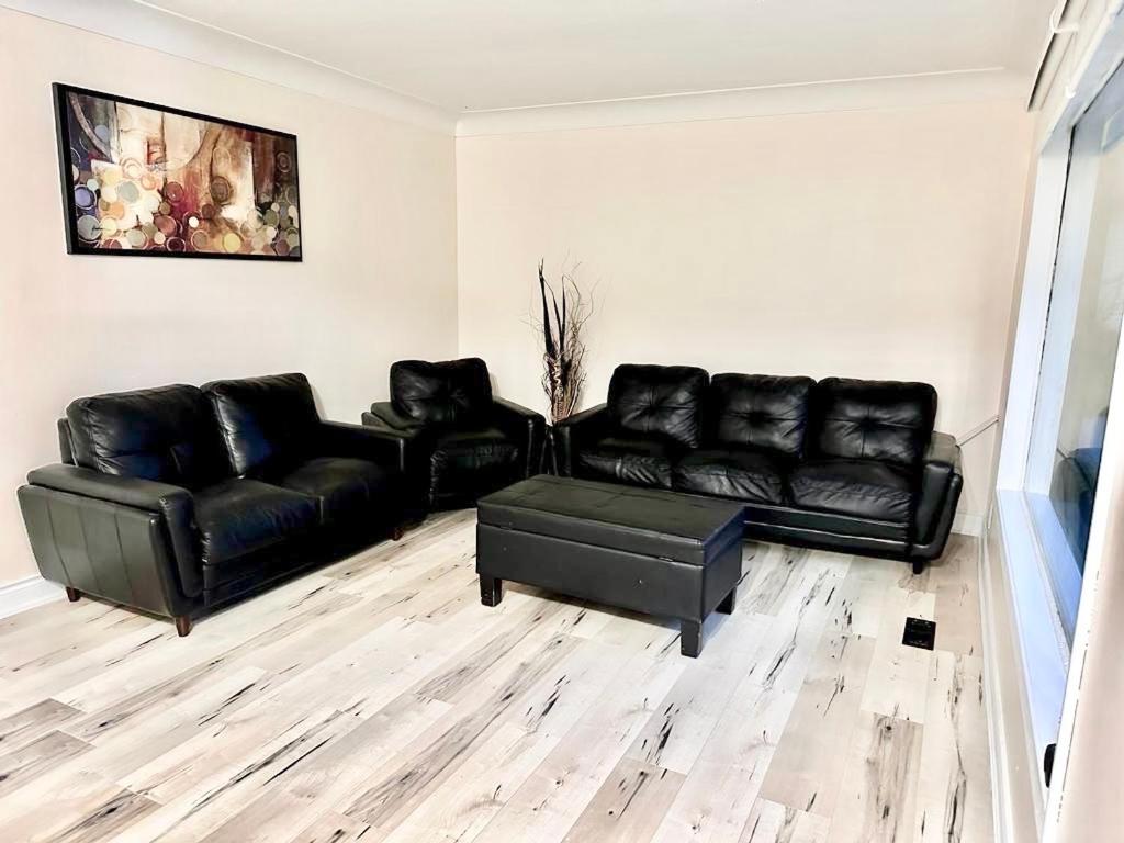 uma sala de estar com sofás de couro preto e uma mesa em Bedroom 1 with free Parking, free wi-fi and shared washroom (Room 1) em Kitchener