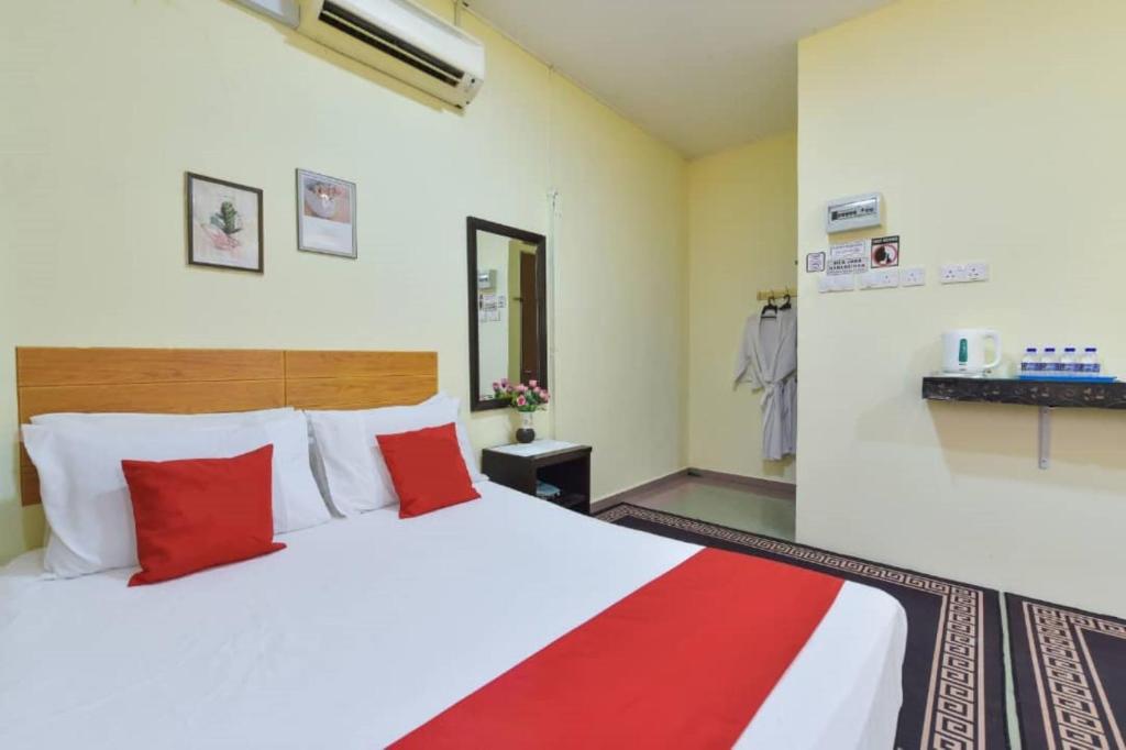 a bedroom with a large white bed with red pillows at Dimensi Hotel in Kampong Alor Gajah