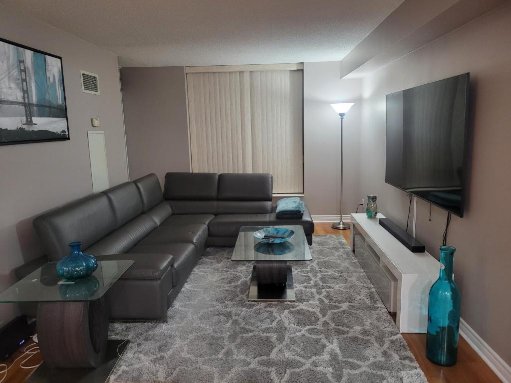a living room with a couch and a flat screen tv at Private Ensuite Room in Luxury Condo in Toronto