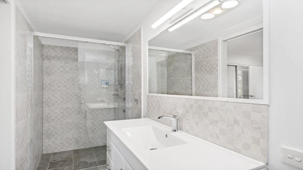 a white bathroom with a sink and a mirror at New With A View Accom Holidays in Copacabana