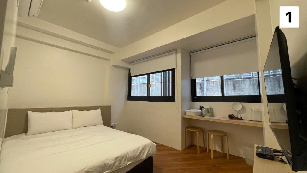 Un dormitorio pequeño con una cama y dos ventanas. en FUNDI Hotel, en Tainan