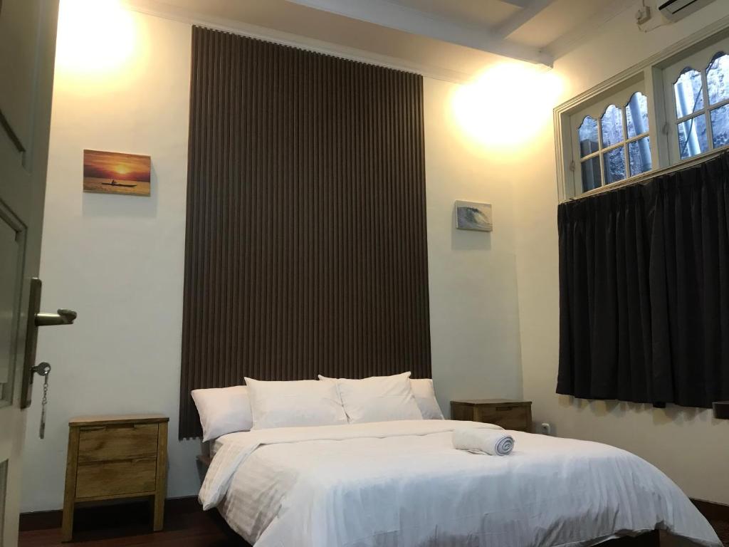 a bedroom with a white bed and a window at Sentosa Lodge in Kampungdurian
