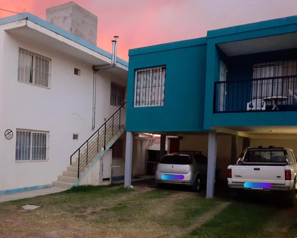 twee auto's geparkeerd voor een gebouw met een balkon bij CASA HOST Las Grutas in Las Grutas