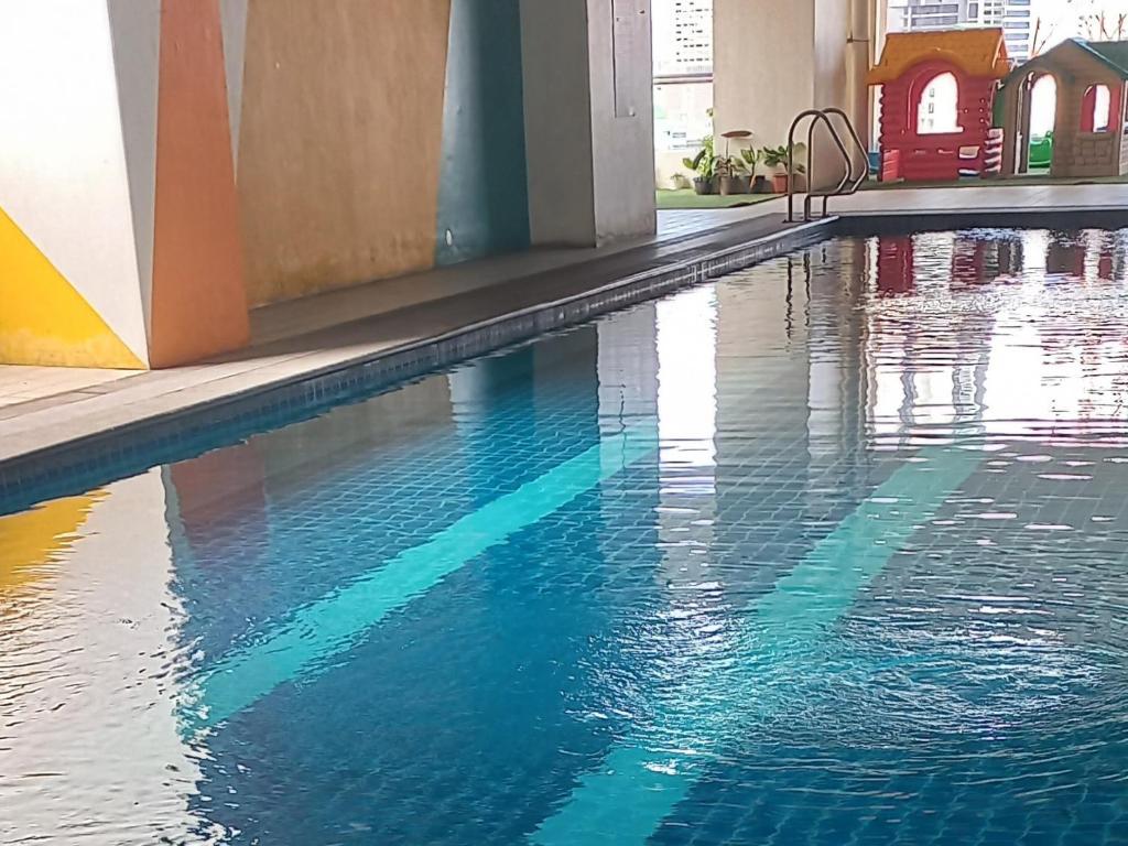 uma piscina com água azul num edifício em Staycation in Quezon City with Netflix and Pool access at Tranquil Space by Ada em Manila