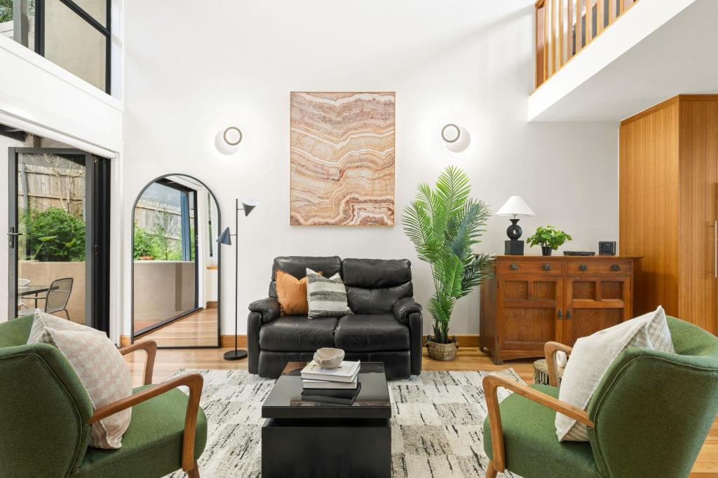 a living room with a black leather couch and chairs at Balmain Retreat - 2BR + Study in Sydney