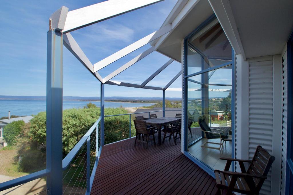 a balcony with a table and chairs and a view of the ocean at Waterline Holiday Home in Coles Bay