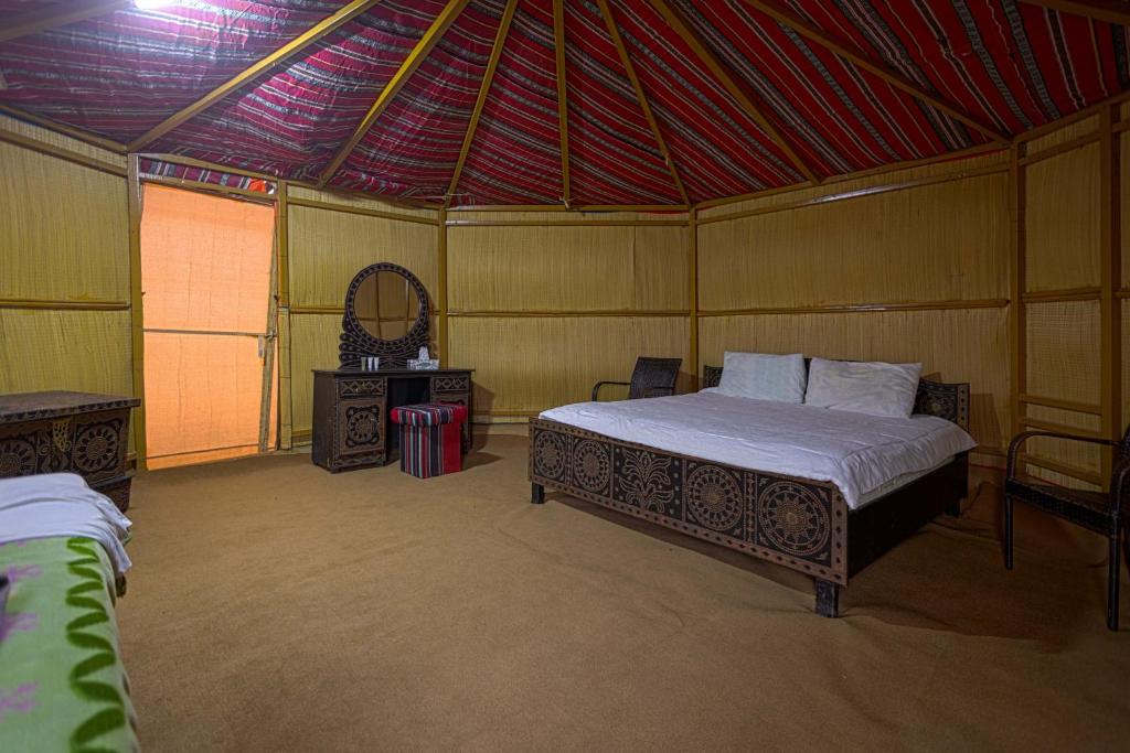 um quarto com uma cama e um espelho numa tenda em SAFARI-Glamping em Al Wāşil