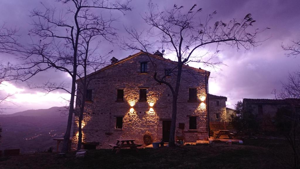 una vieja casa de piedra con luces encendidas por la noche en Bed and Breakfast Ballallaluna, en Maiolo