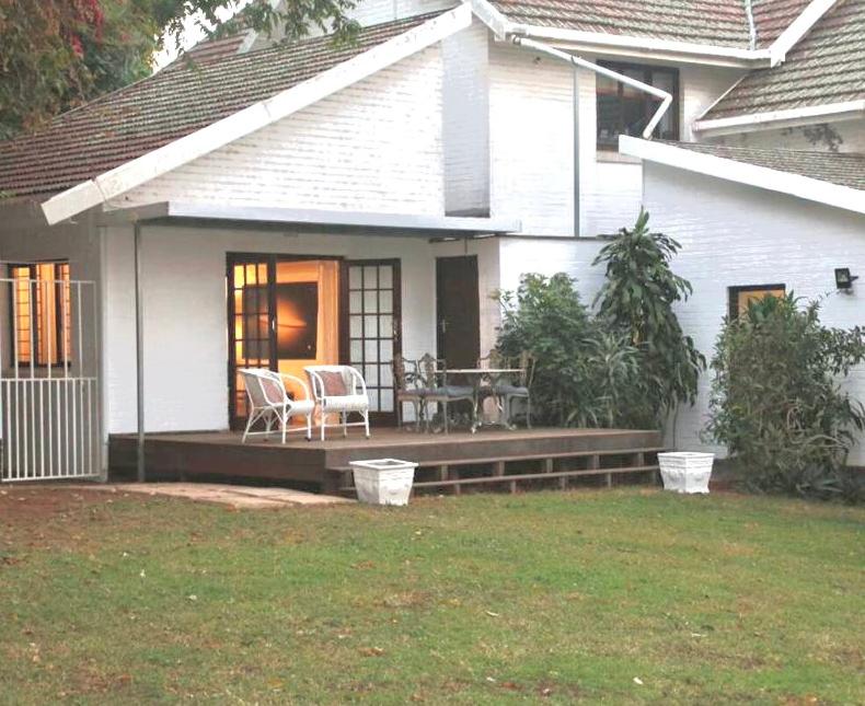 Casa con porche con mesa y sillas en Sherwood Garden Cottage en Durban