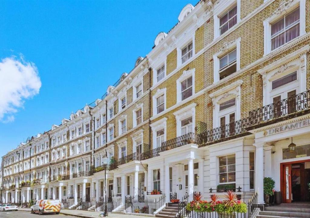 un gran edificio con columnas blancas y balcones en una calle en Kensington & Chelsea - Stylish Apartment in Central London, en Londres