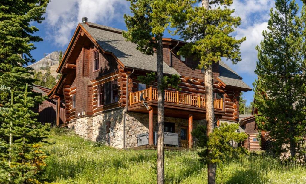 une maison en rondins avec une terrasse sur une colline dans l'établissement Powder Ridge Cabin Rosebud 7, à Big Sky