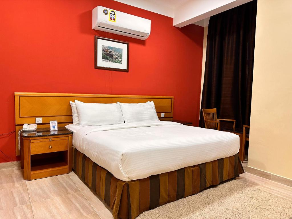 a bedroom with a bed and a red wall at Remal Ibri hotel in ‘Ibrī