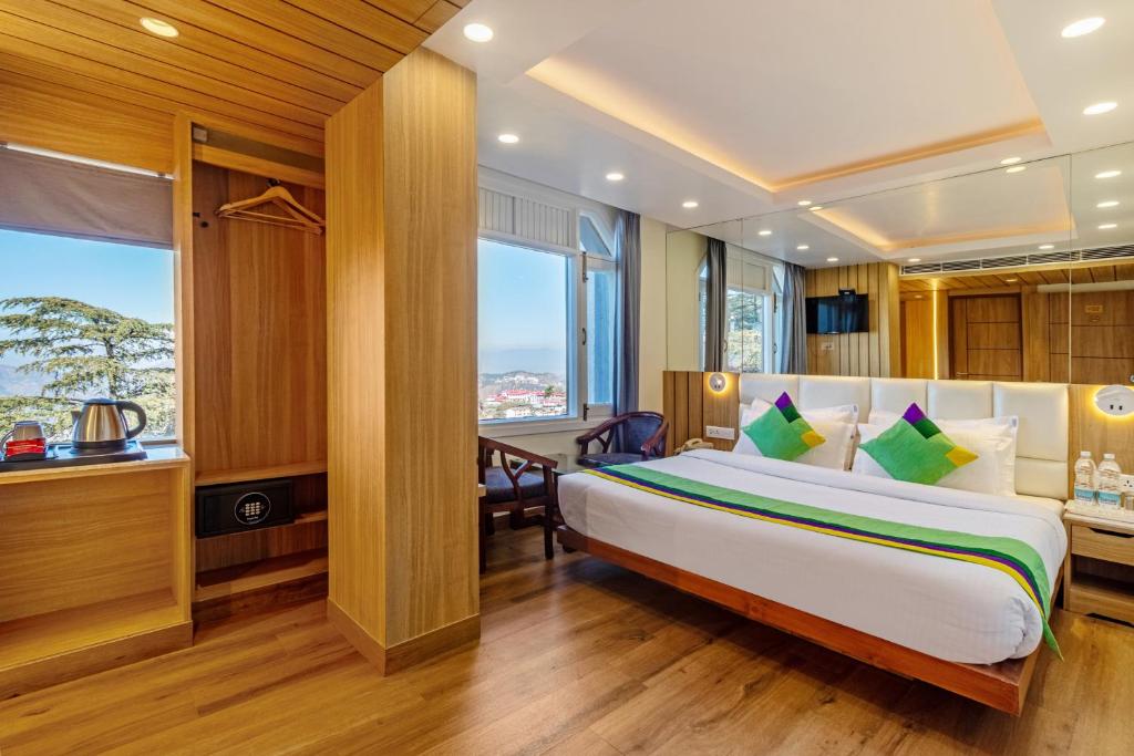 - une chambre avec un grand lit et une fenêtre dans l'établissement Treebo Trend Varuna With Mountain View, à Shimla