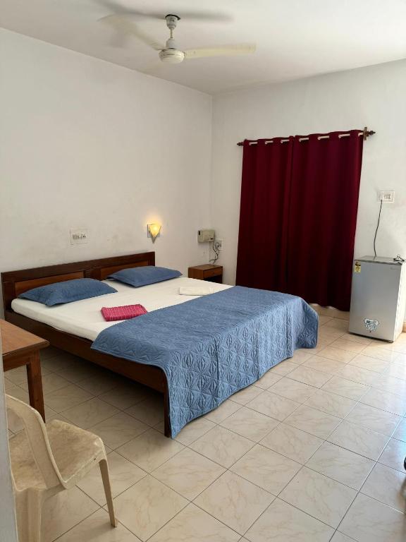 a bedroom with a large bed with a red curtain at VILLA SOL BEACH RESORT in Baga