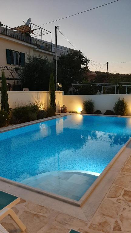 a large blue swimming pool in front of a building at The Central Residence - Kassiopi Corfu Villas in Kassiopi