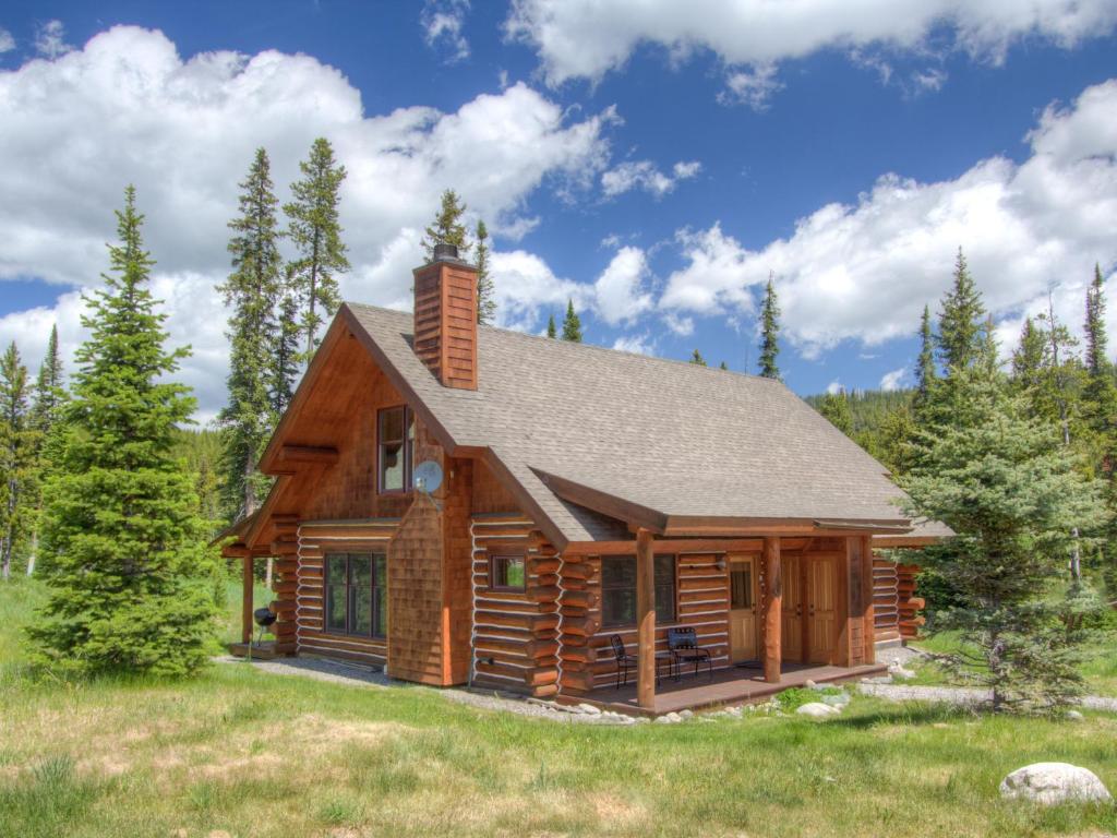eine Blockhütte auf einem Feld mit Bäumen in der Unterkunft Powder Ridge Cabin Moose Ridge 5 in Gallatin Gateway