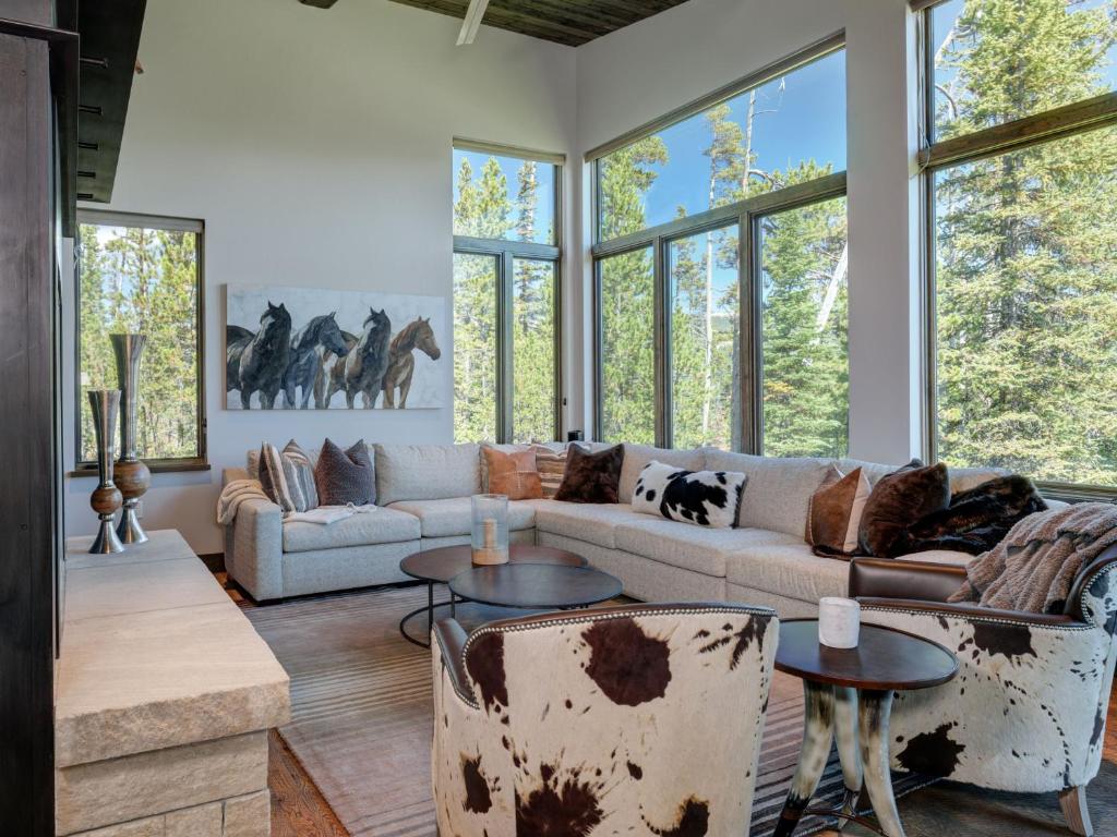 a living room with a couch and tables and windows at Homestead Chalet 6 Claim Jumper in Big Sky