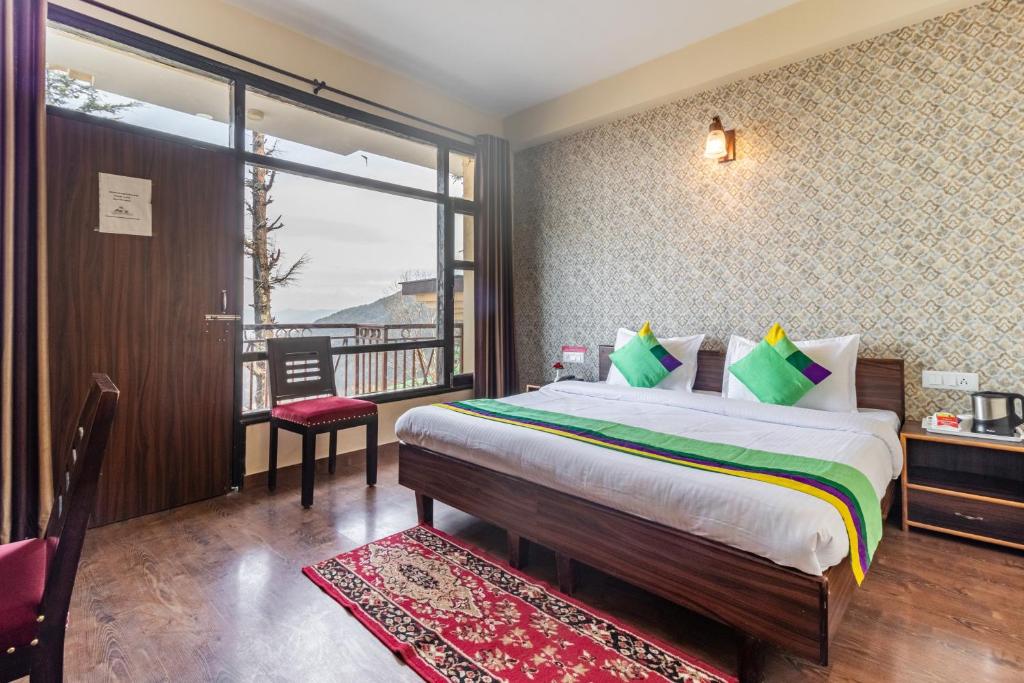 a bedroom with a large bed and a balcony at Treebo Trend Shimla Ayurvedic Retreat Kufri in Kūfrī