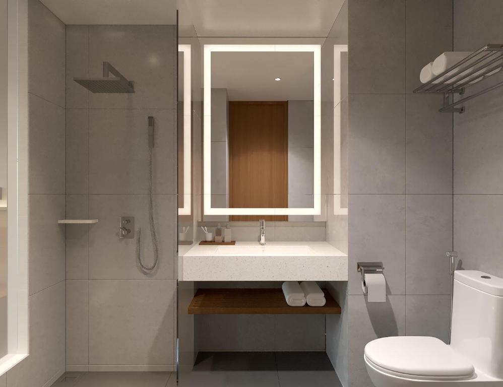 bagno con lavandino, specchio e servizi igienici di ASTON Palu Hotel & Conference Center a Palu