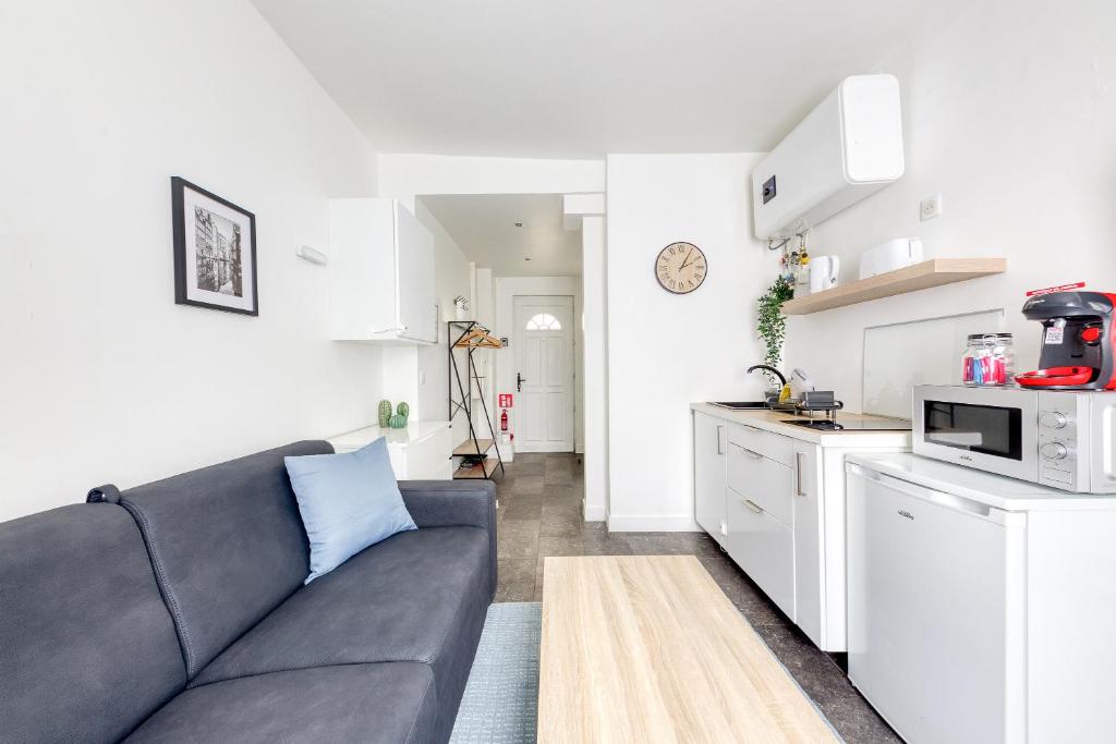 un salon avec un canapé et une cuisine dans l'établissement Studio Cosy - proche Paris & Stade de France, à Pantin