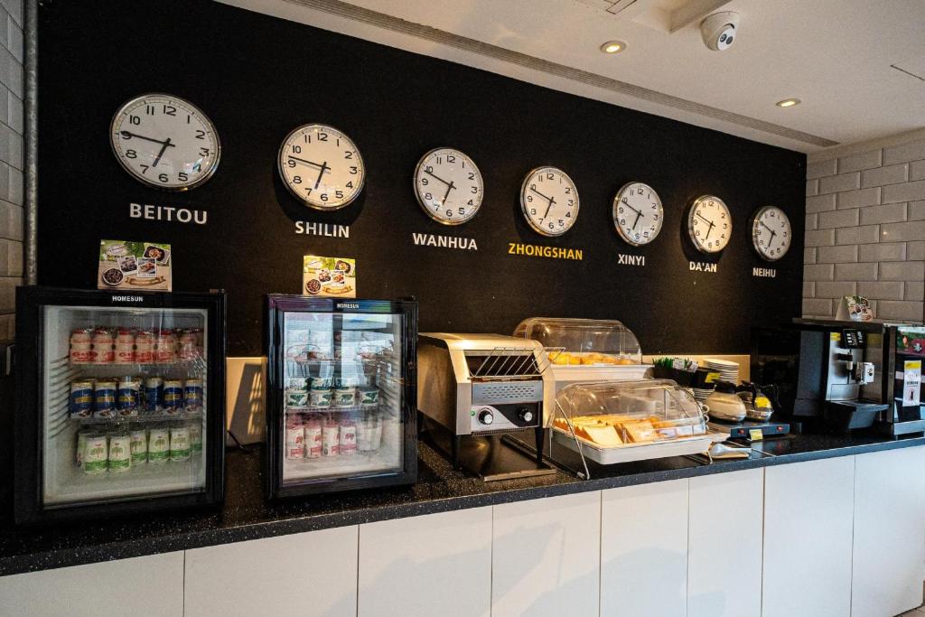 a row of clocks on a wall above a counter at CHECK inn Taipei Songjiang in Taipei