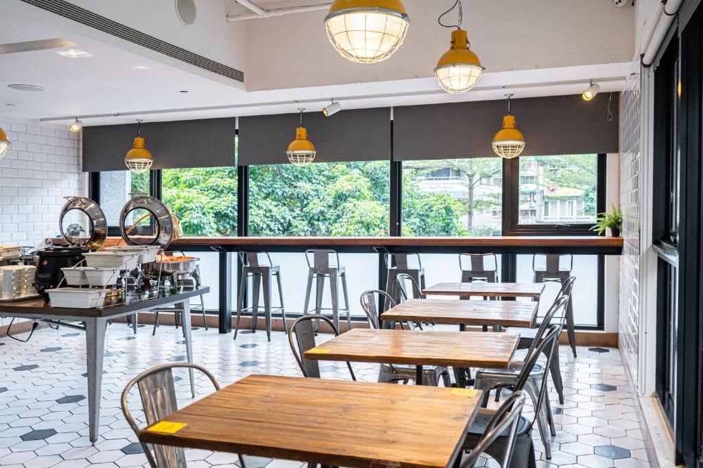 a restaurant with wooden tables and chairs and windows at CHECK inn Taipei Songjiang in Taipei