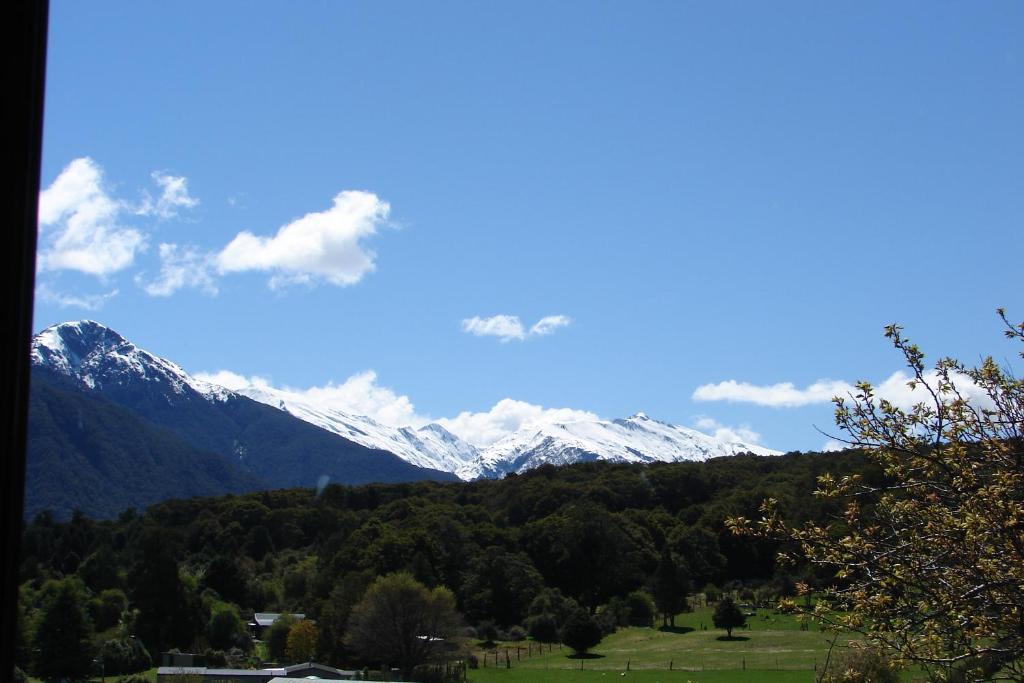 a view of snow capped mountains from a field at Mountainview Makarora Accommodation in Makarora