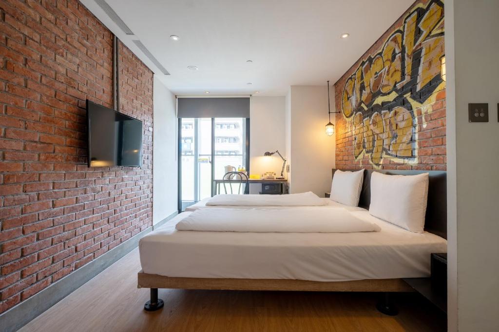 two beds in a room with a brick wall at CHECK inn Taipei Songjiang in Taipei
