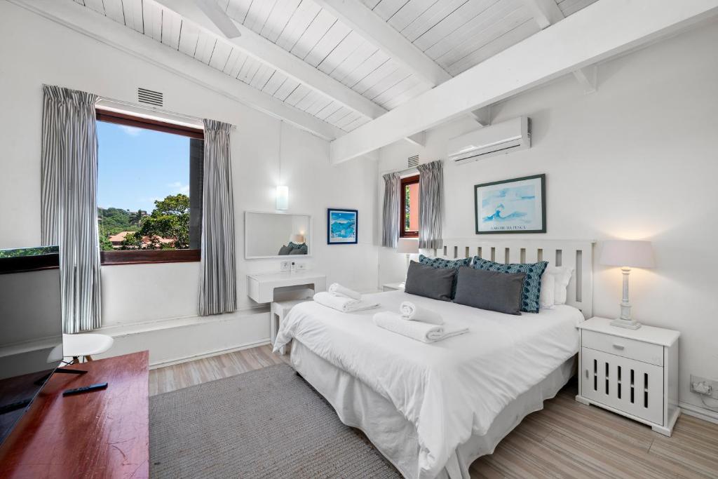 een witte slaapkamer met een groot bed en een raam bij San Lameer Villa 3008 - 4 Bedroom Classic - 8 pax - San Lameer Rental Agency in Southbroom