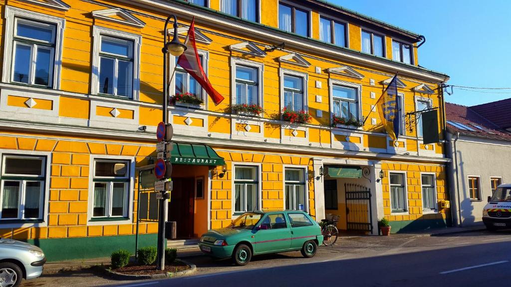 einem grünen Auto, das vor einem gelben Gebäude parkt in der Unterkunft Pension Zierlinger in Senftenberg