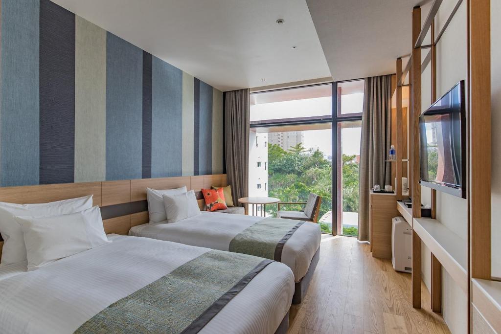 那覇市にあるJR九州ホテル ブラッサム那覇のベッド2台とテレビが備わるホテルルームです。