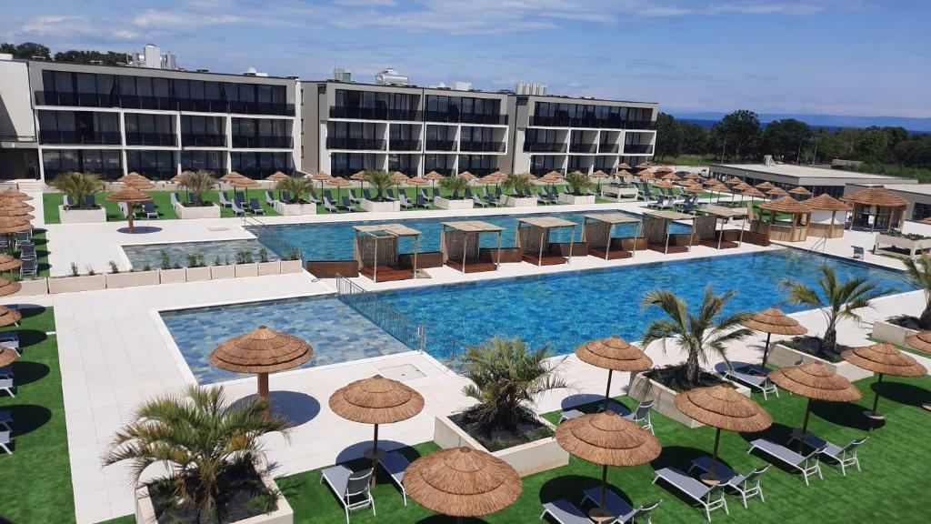 een uitzicht over een resort met een zwembad, stoelen en parasols bij Hotel Del Mar Emotion in Pula