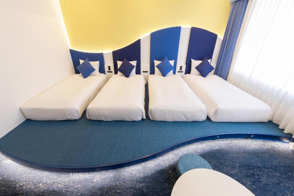 two beds in a room with blue and white at Hotel Keihan Universal Tower in Osaka