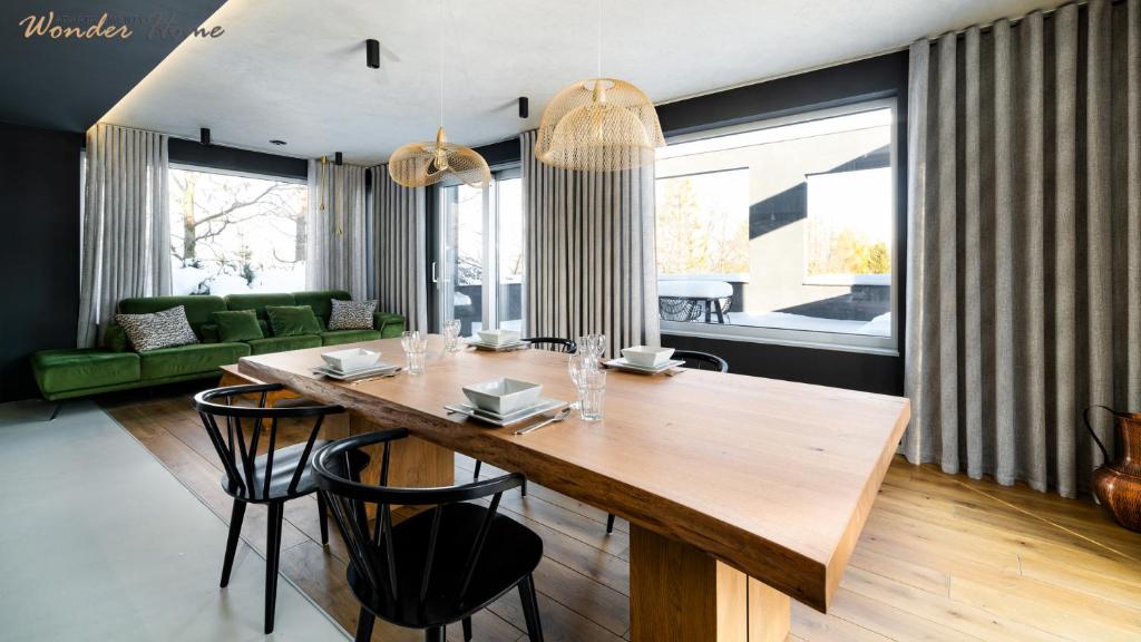 uma sala de jantar com uma mesa de madeira e cadeiras em Wonder Home - Luksusowy dom Casa Moderna z dwoma tarasami w cichej okolicy blisko Karpacza em Kowary