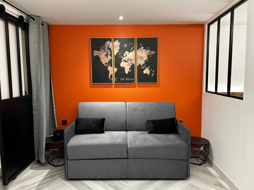 un divano in una camera con parete arancione di L'Orfèvrerie a Bourges