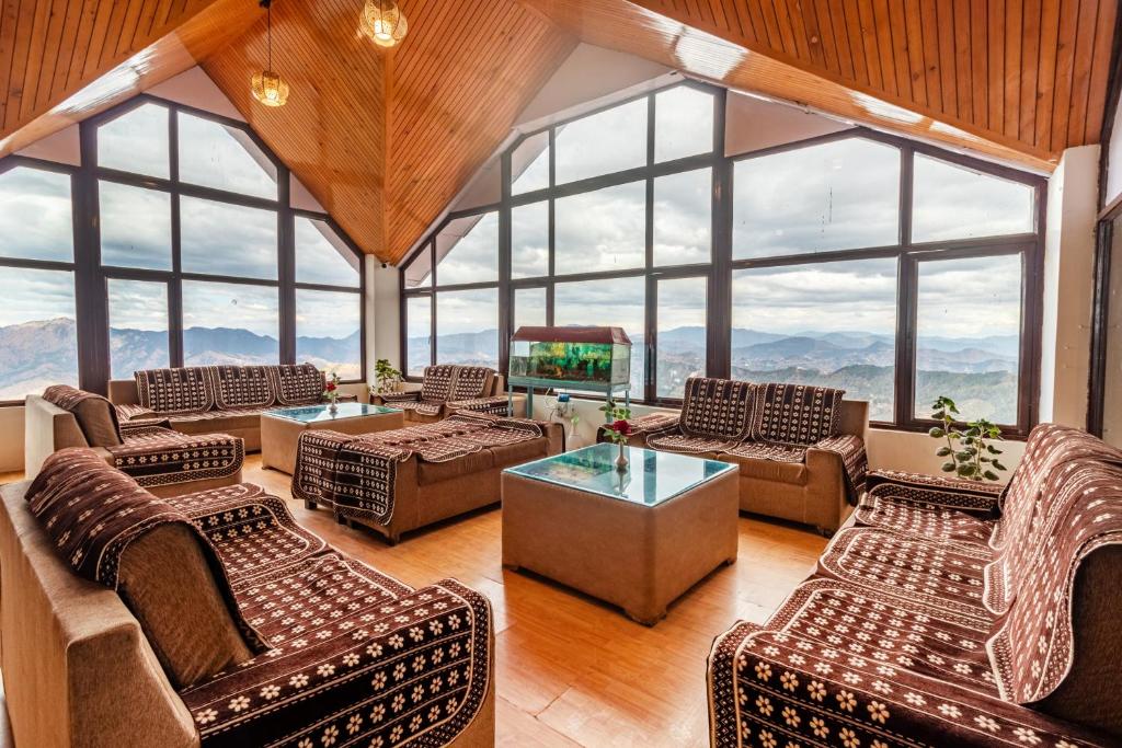 a living room with large windows and a television at Treebo Trend Snow View Resort Kufri With Mountain View in Shimla