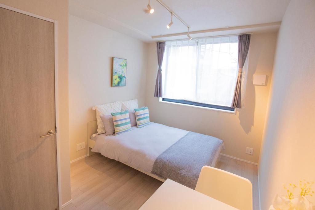 Habitación pequeña con cama y ventana en Your best choice for travel in Yoyogi Y01g, en Tokio