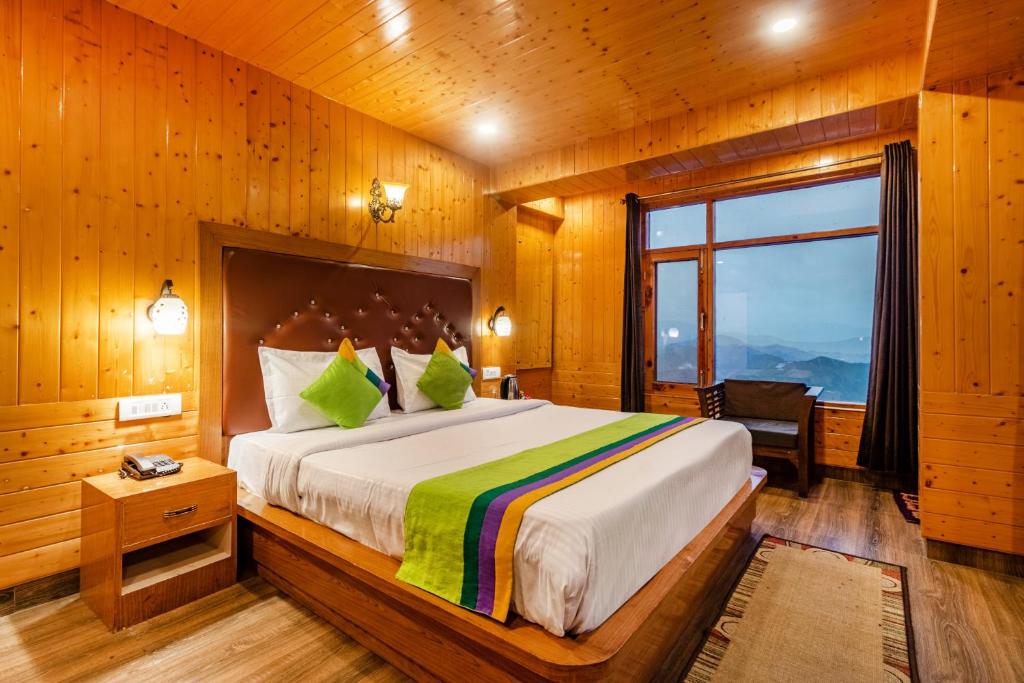 a bedroom with a large bed in a wooden room at Treebo Trend Snow View Resort in Shimla