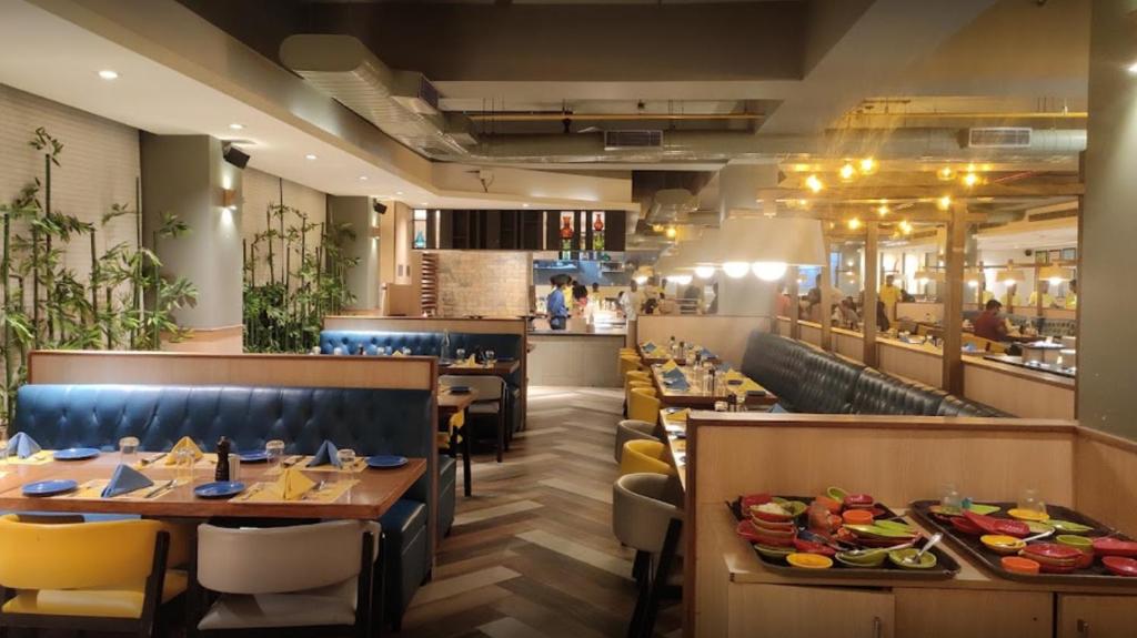 un restaurante con mesas y sillas de madera y un buffet en ASTRA HOTELS & SUITES WHITEFIELD NEAR TO NALLURAHALLI METRO STATION and KTPO en Bangalore