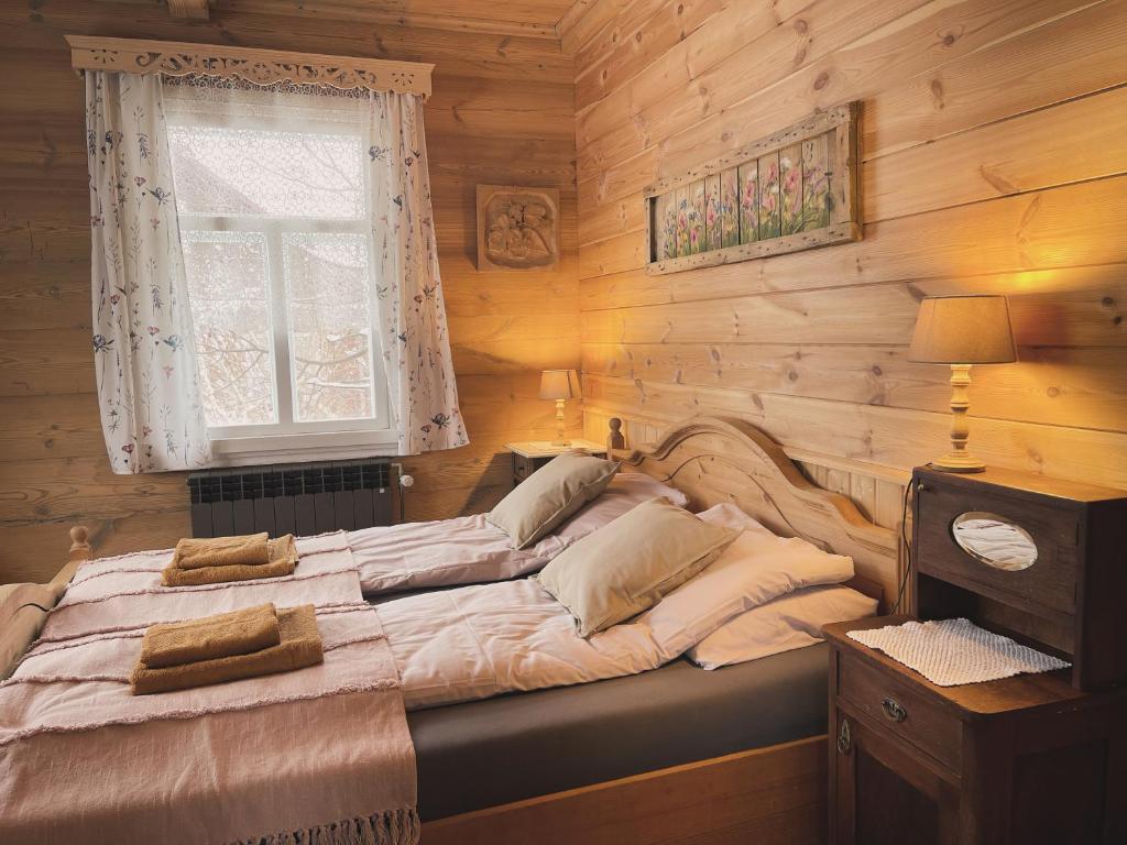 a large bed in a wooden room with a window at Aczarowane Kojły 7 in Kojły