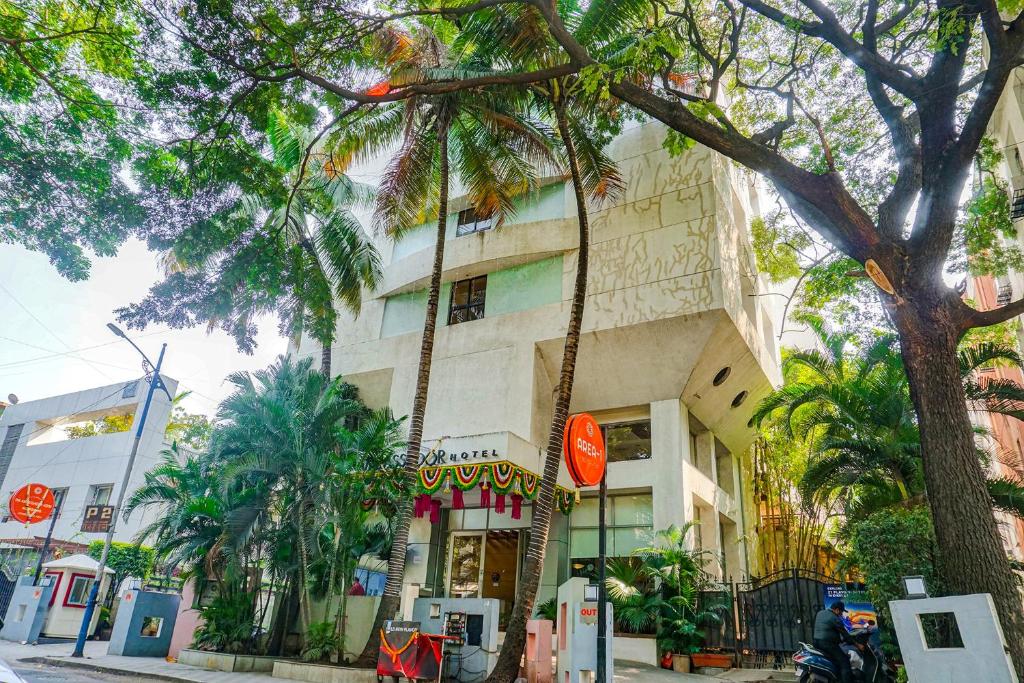 a building on the side of a street with palm trees at FabHotel Prime Ambassador in Pune