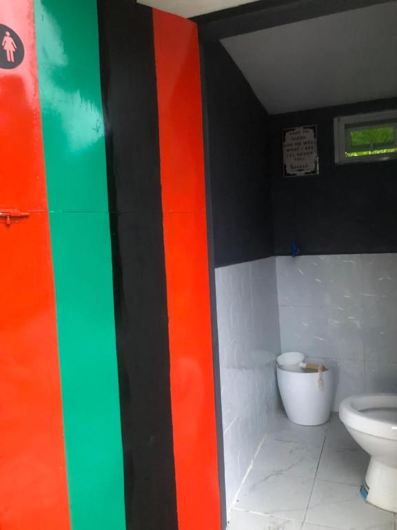 a bathroom with a toilet and a colorful wall at Little Cabins at Km 499 