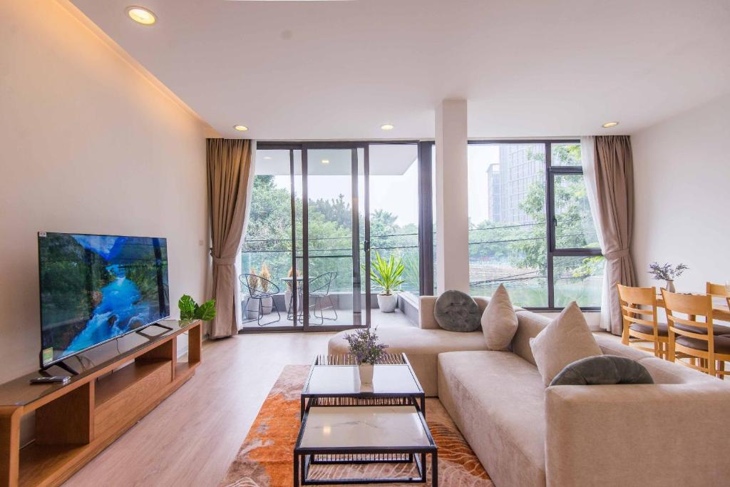 ein Wohnzimmer mit einem Sofa und einem Flachbild-TV in der Unterkunft Luxe Paradise Residence 9 Quang Khanh in Hanoi