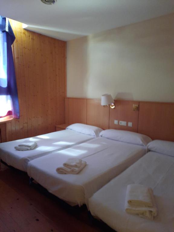 Dos camas en una habitación de hotel con toallas. en Hostal Pico Agujas, en San Isidro