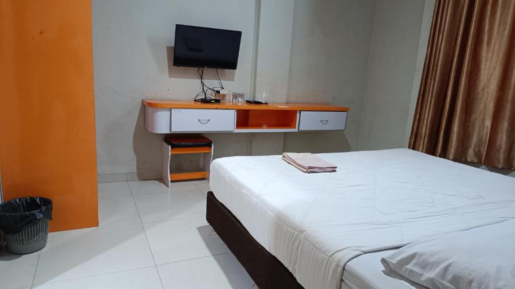a bedroom with a bed and a desk with a television at IHomestay Pekanbaru in Pekanbaru