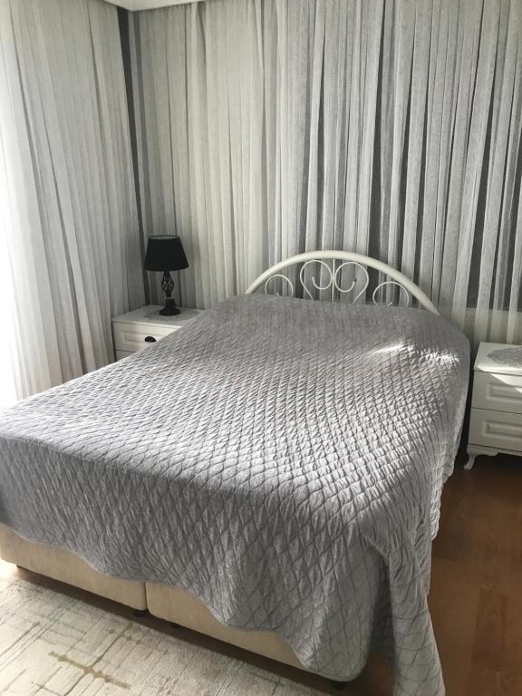 1 dormitorio con 1 cama con edredón gris en ömerin evi, en Akyazı