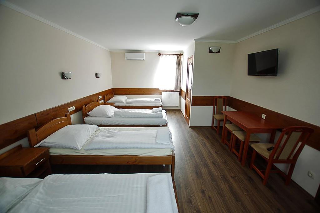 ソンバトヘイにあるKispipa Panzióのベッド3台、デスク、テレビが備わる客室です。