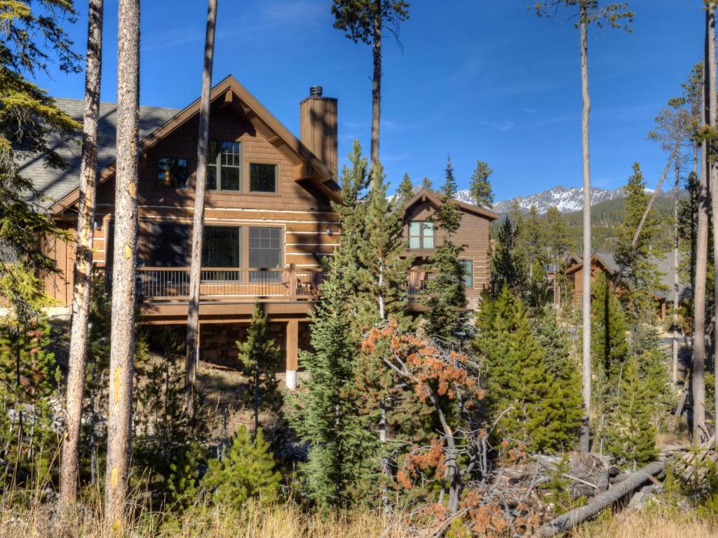 uma casa de madeira rodeada por árvores em Powder Ridge Cabin Oglala 2B em Big Sky