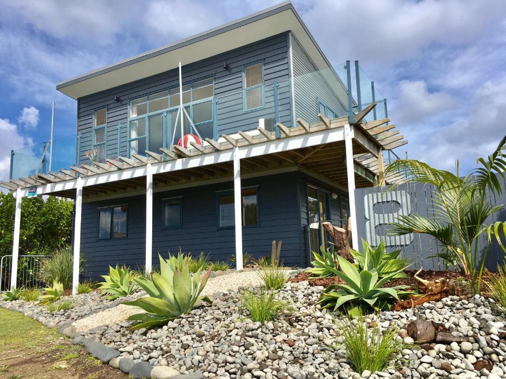 a blue house with a porch and a yard at Oceans 8 - Mangawhai Heads Holiday Home in Mangawhai